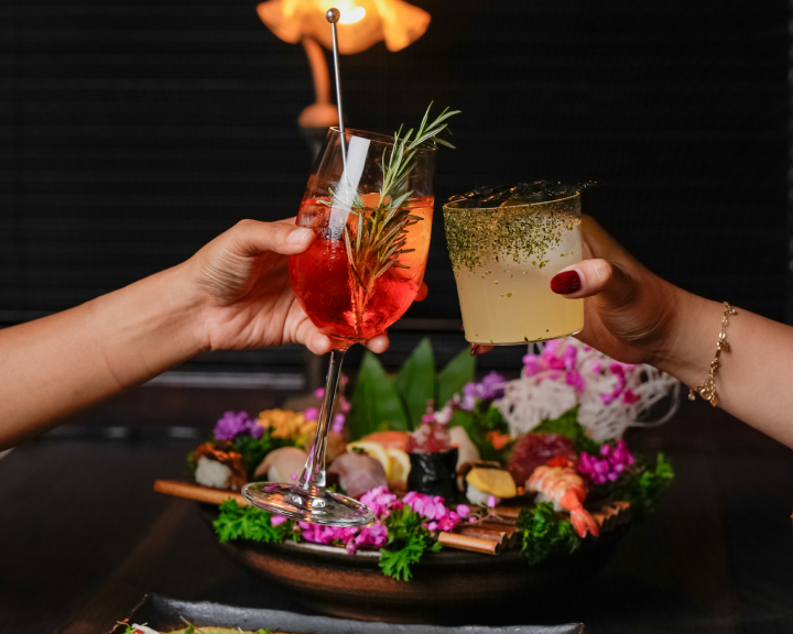 Guests toasting cocktails over sushi platter at Kajin Japanese restaurant Bali